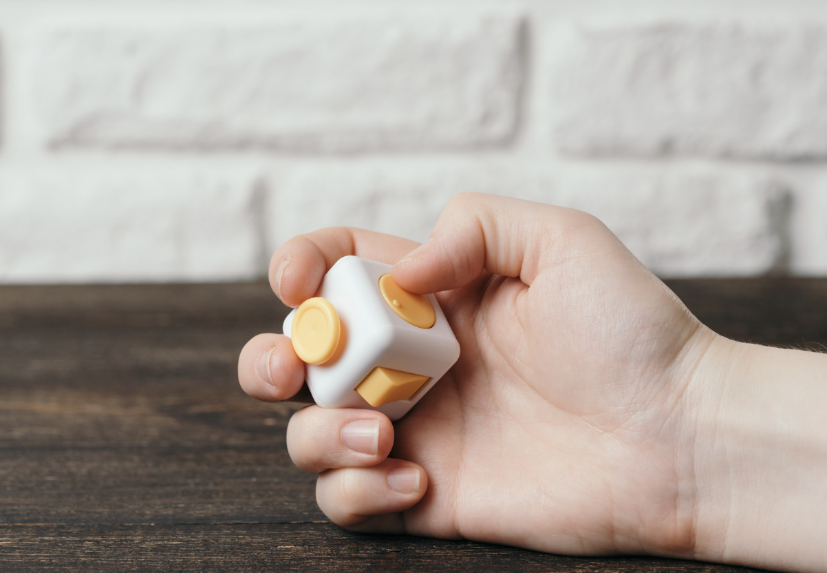 Picture shows hand using a fidget toy demonstrating the benefits of fidget toys.